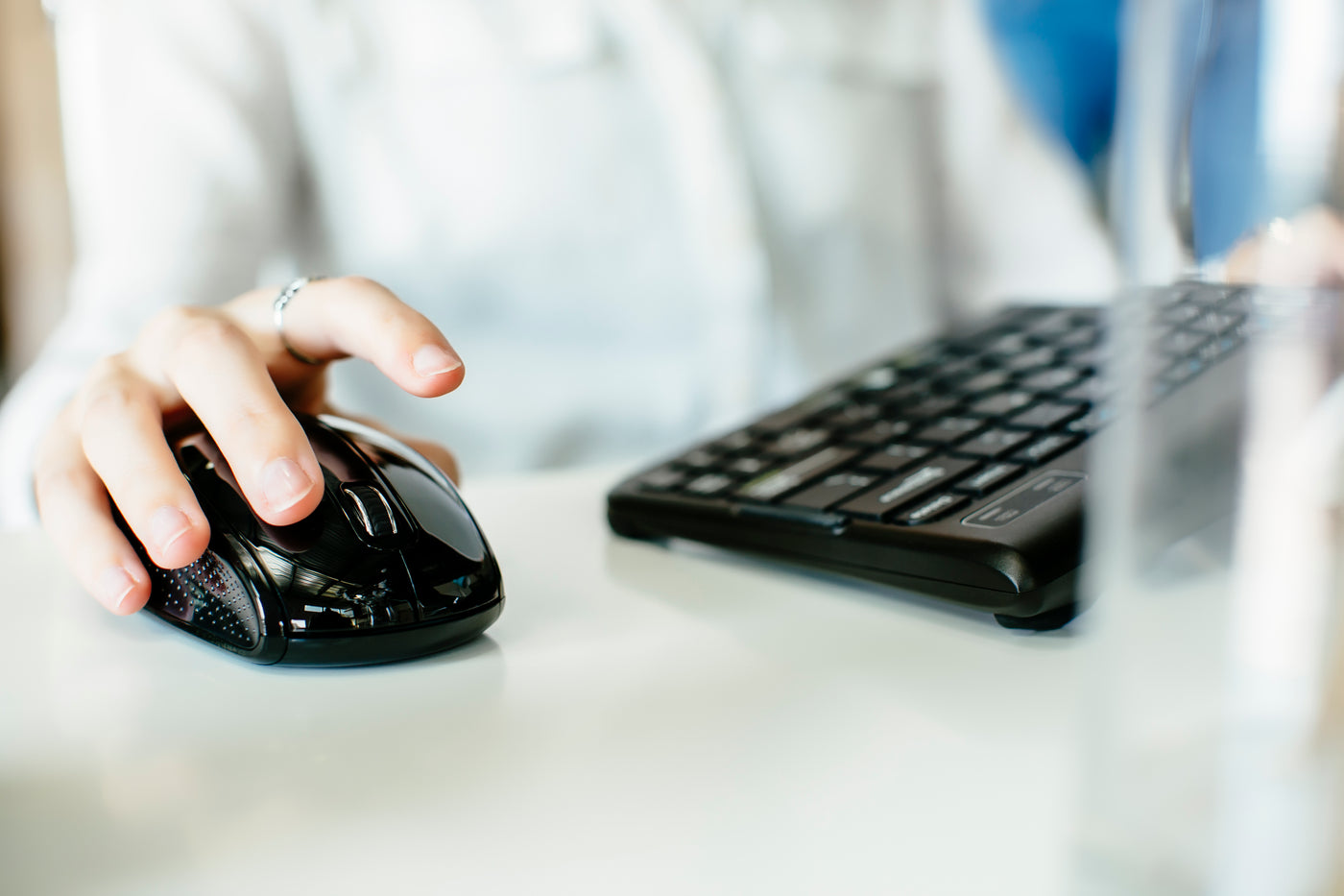Closeup on a female office worker using her finger to click an ambidextrous mouse and typing on a Go!2 Mobile Keyboard.