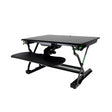 An adjustable Goldtouch EasyLift Sit/Stand Desk with a black tabletop and a sliding keyboard tray, featuring green accents on the side knobs.