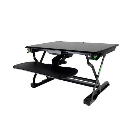An adjustable Goldtouch EasyLift Sit/Stand Desk with a black tabletop and a sliding keyboard tray, featuring green accents on the side knobs.