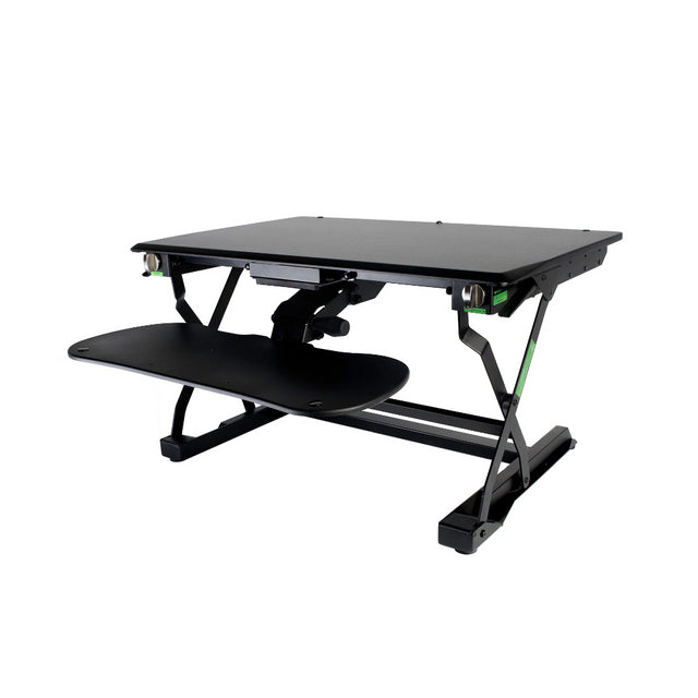 An adjustable Goldtouch EasyLift Sit/Stand Desk with a black tabletop and a sliding keyboard tray, featuring green accents on the side knobs.